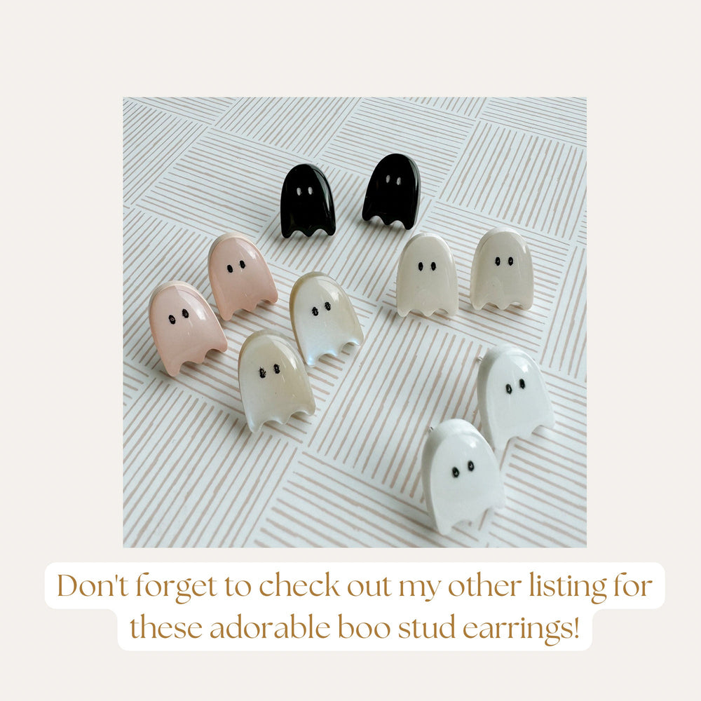A collection of ghost-shaped stud earrings in various colors, including black, white, and pastel shades. The earrings have small, dot-like eyes. The image includes the text: "Don't forget to check out