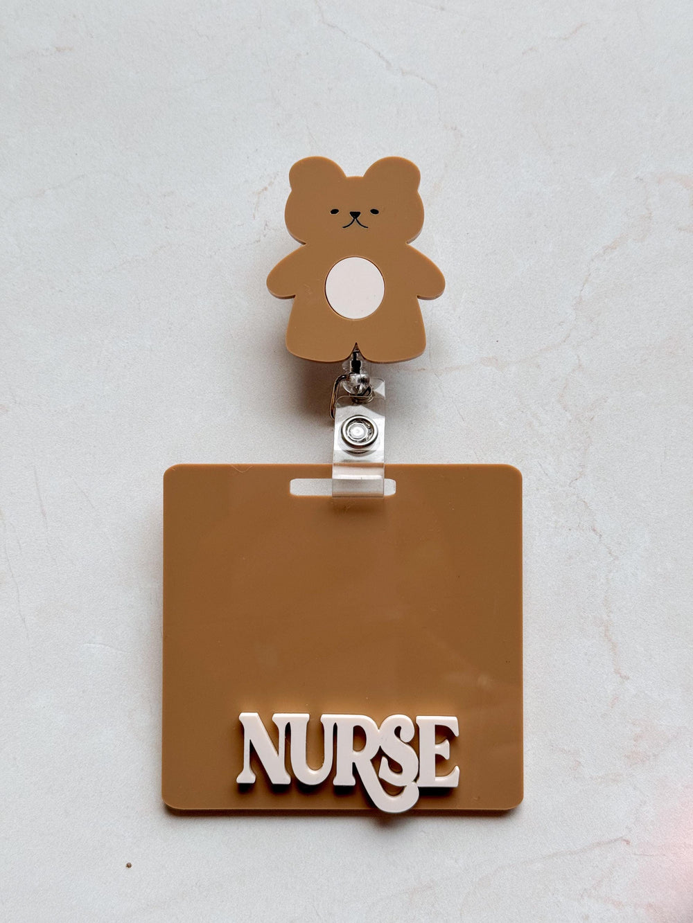 A brown plastic badge holder with a brown bear charm and the word "" in white letters.