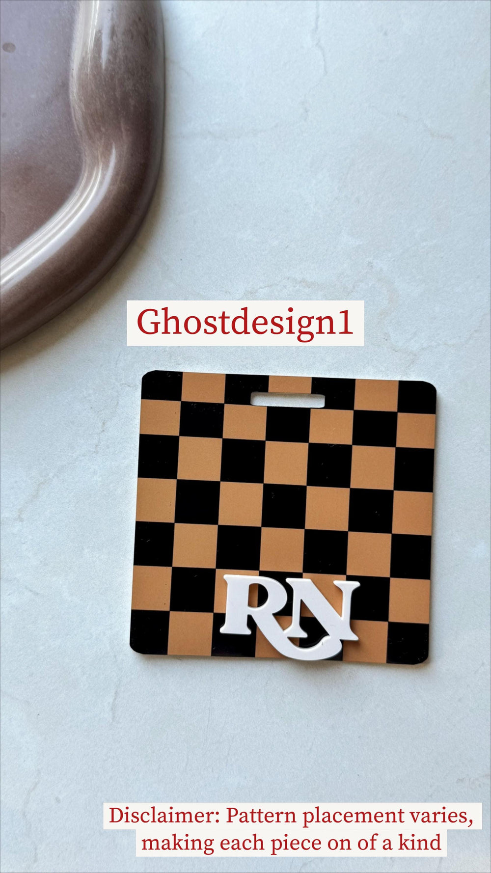 A black and tan checkered name tag with a white "" design. The tag has a rectangular shape with a slot at the top. The text "Ghostdesign1" is above the tag.