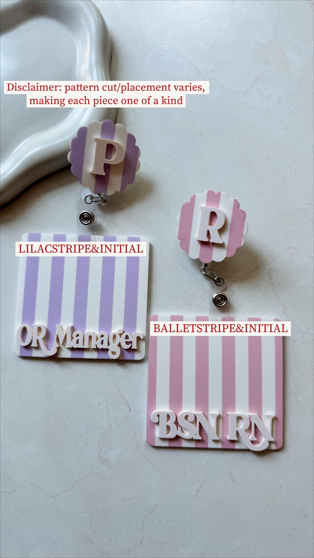 Two badge reels with striped backgrounds and white lettering. One has a lilac and white stripe with "OR Manager" text. The other has a pink and white stripe with "BSN " text. Both have initial toppers