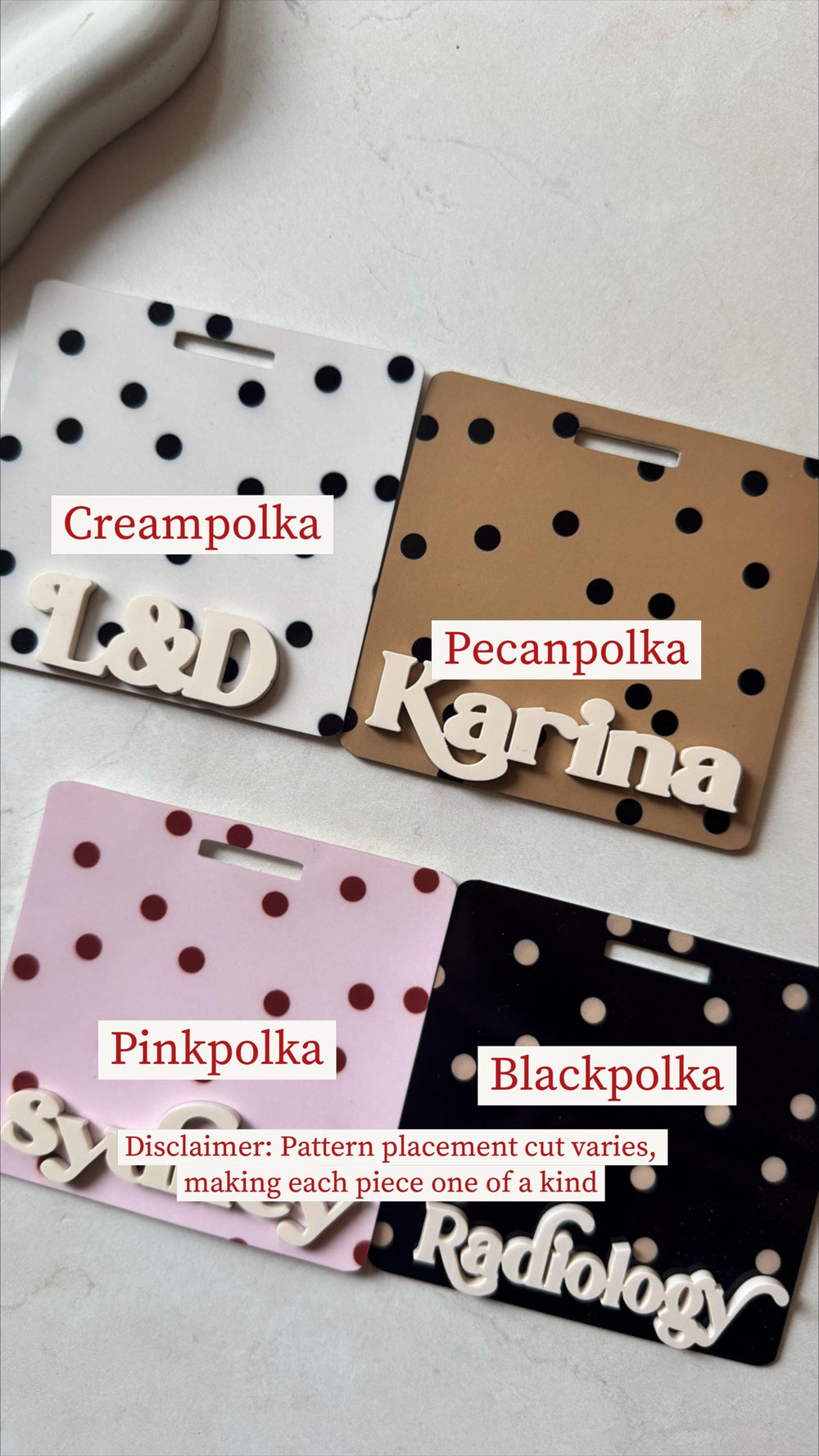 Four name badge holders with polka dot patterns in cream, brown, pink, and black. Each badge has a name or initials in white, with the text "" on the black badge. The text "Disclaimer: Pattern placeme