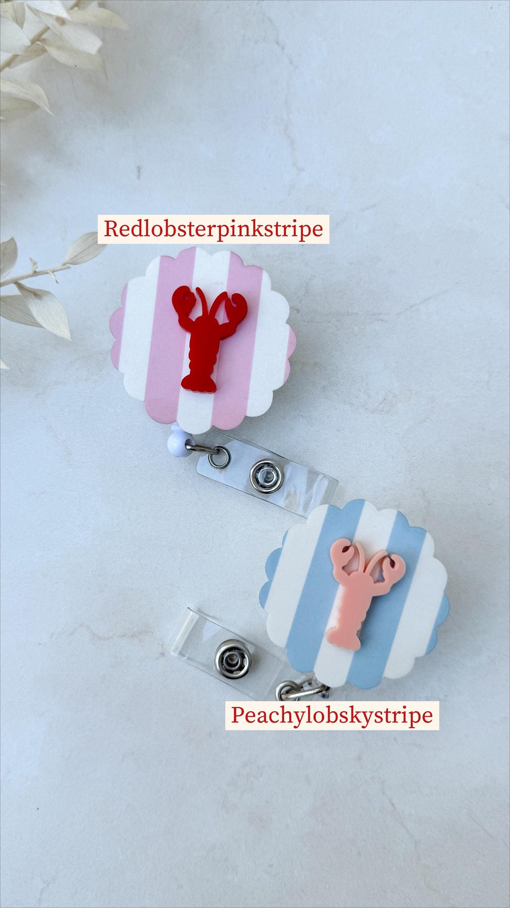 Two badge reels with scalloped edges. One has pink and white stripes with a red lobster, the other has blue and white stripes with a peach lobster. Text on the badges reads "Redlobsterpinkstripe" and 