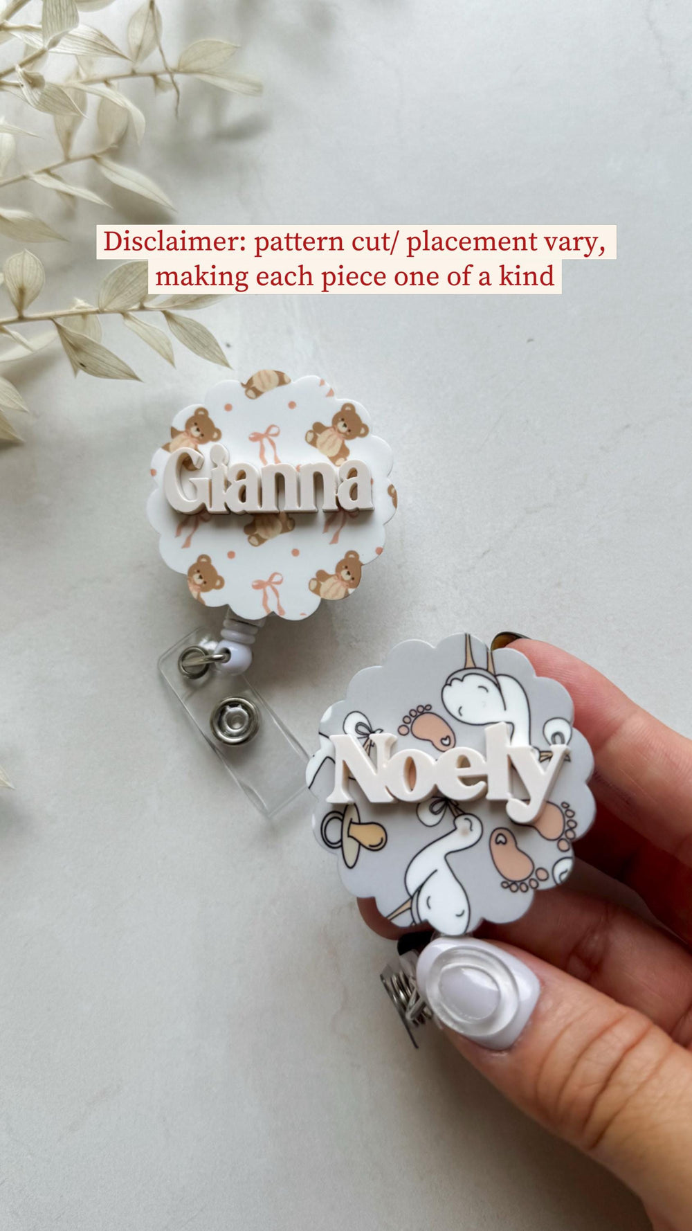 Two personalized badge reels. One features the name "Gianna" on a white background with teddy bear and bow patterns. The other has the name "Noely" on a gray background with baby-themed illustrations.