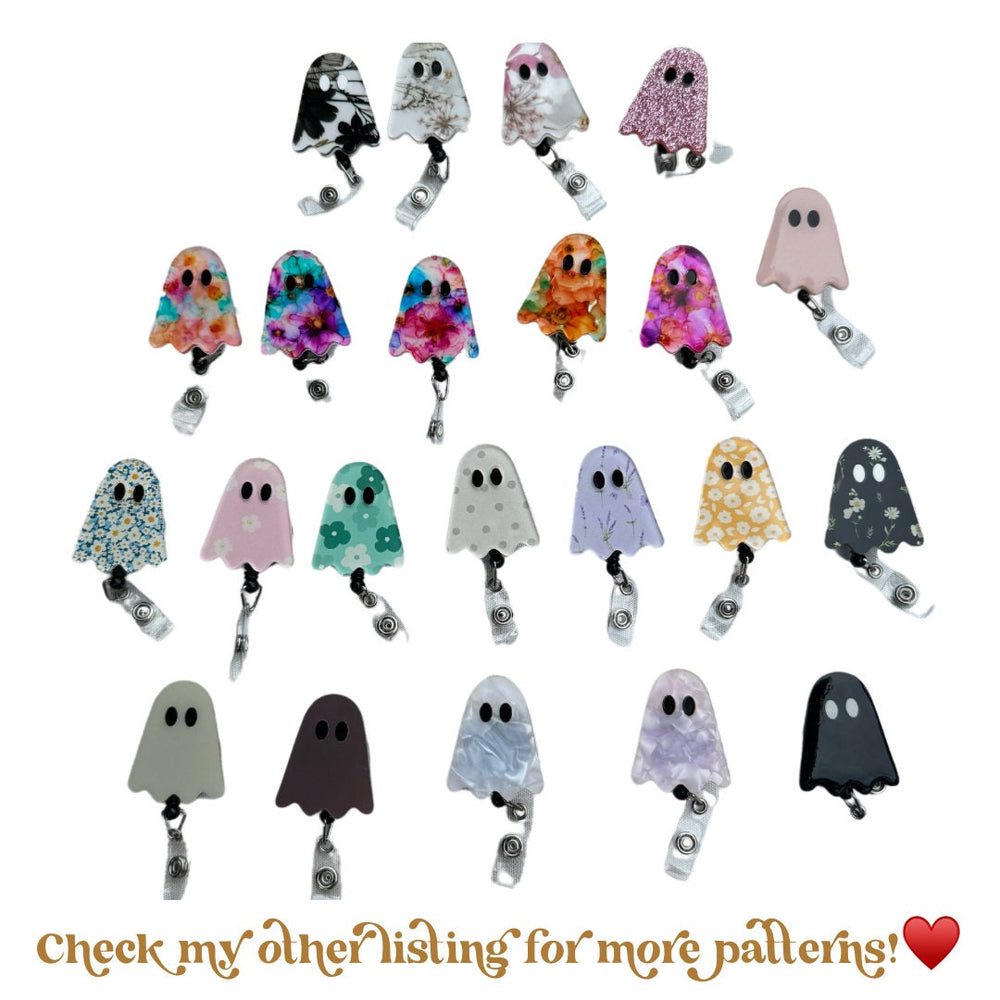 A collection of ghost-shaped badge reels in various patterns and colors. Designs include floral, glitter, and solid colors. Each reel has a retractable cord and a clip for attaching to clothing or acc