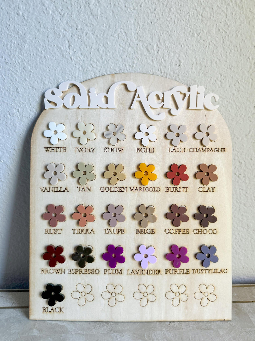 A wooden display board with the words "Solid Acrylic" at the top. The board shows 16 different colors of acrylic in the shape of a flower. The colors are: white, ivory, snow, bone, lace, champagne, va