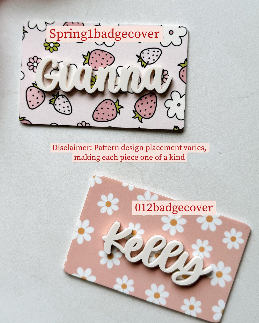 Two badge covers with names. One has a pink strawberry pattern with the name "Gianna" in white script. The other has a pink daisy pattern with the name "Kelly" in white script. The text "Spring1badgec