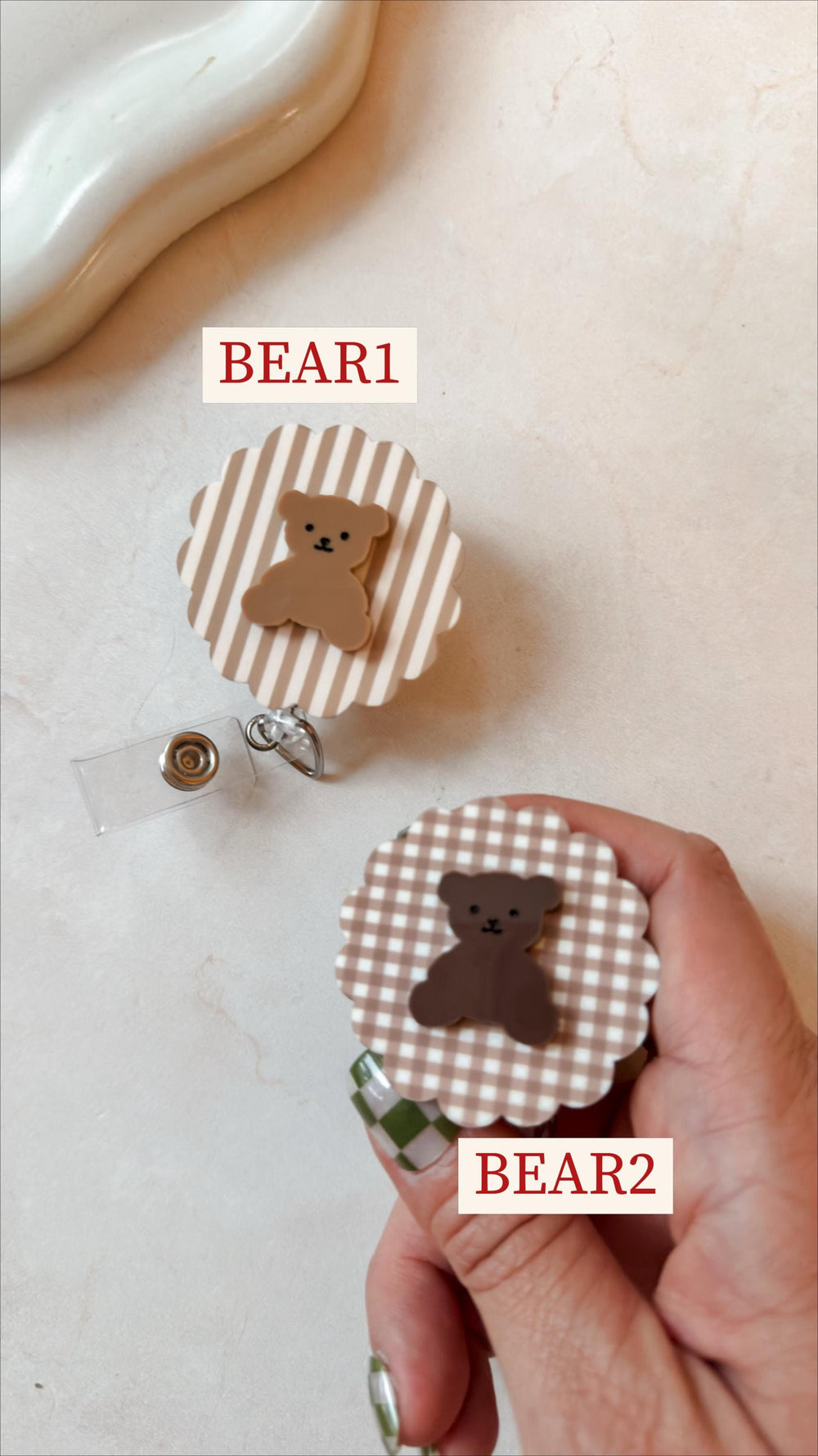 Two badge reels with bear designs. One has a brown and white striped background, the other a brown and white checkered pattern. Both have a brown bear figure in the center. The text "BEAR1" and "BEAR2