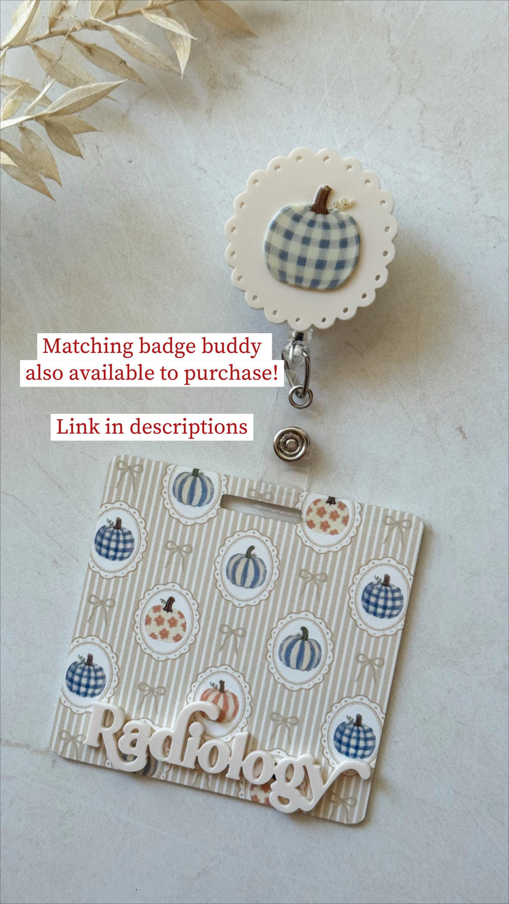A retractable badge reel featuring a white scalloped edge and a blue gingham pumpkin topper, attached to a rectangular badge buddy with a beige striped background, pumpkin illustrations, and the white