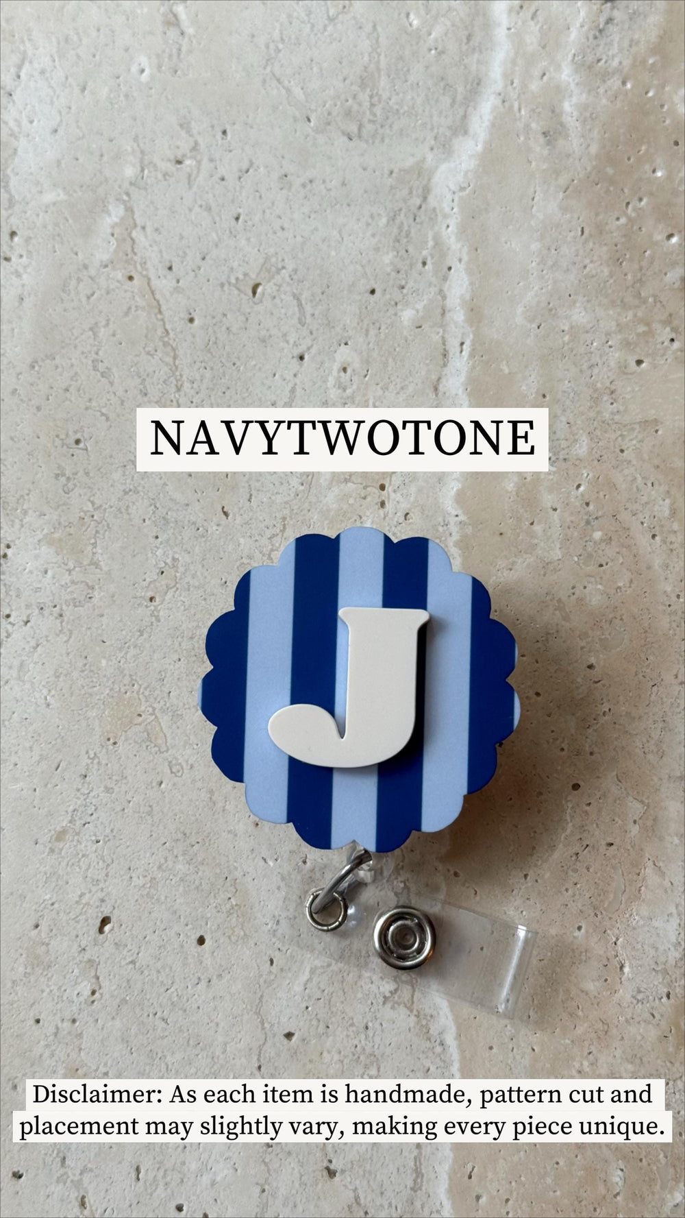 A navy blue and light blue badge reel with a white letter "J" in the center. The badge reel has a scalloped edge and a retractable cord with a metal clip. The text "NAVYTWOTONE" is at the top.