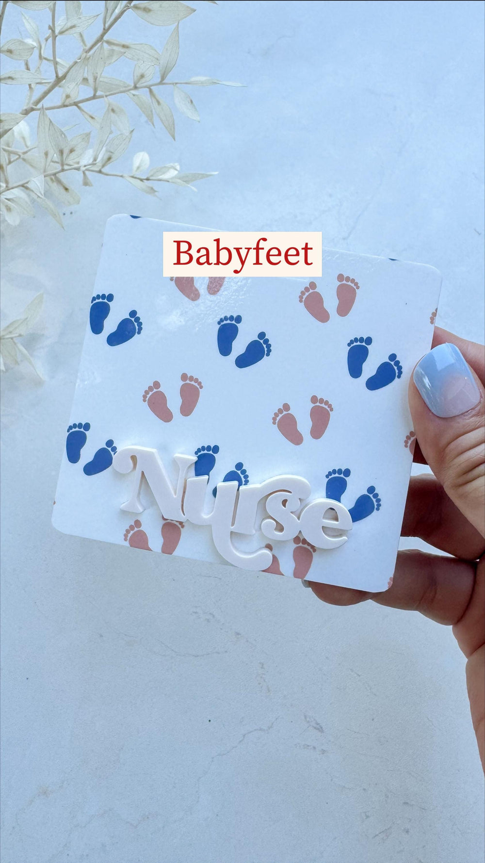 A white square with blue and pink baby footprints. The word "Babyfeet" is in a red rectangle at the top. The word "" is in white, three-dimensional letters.