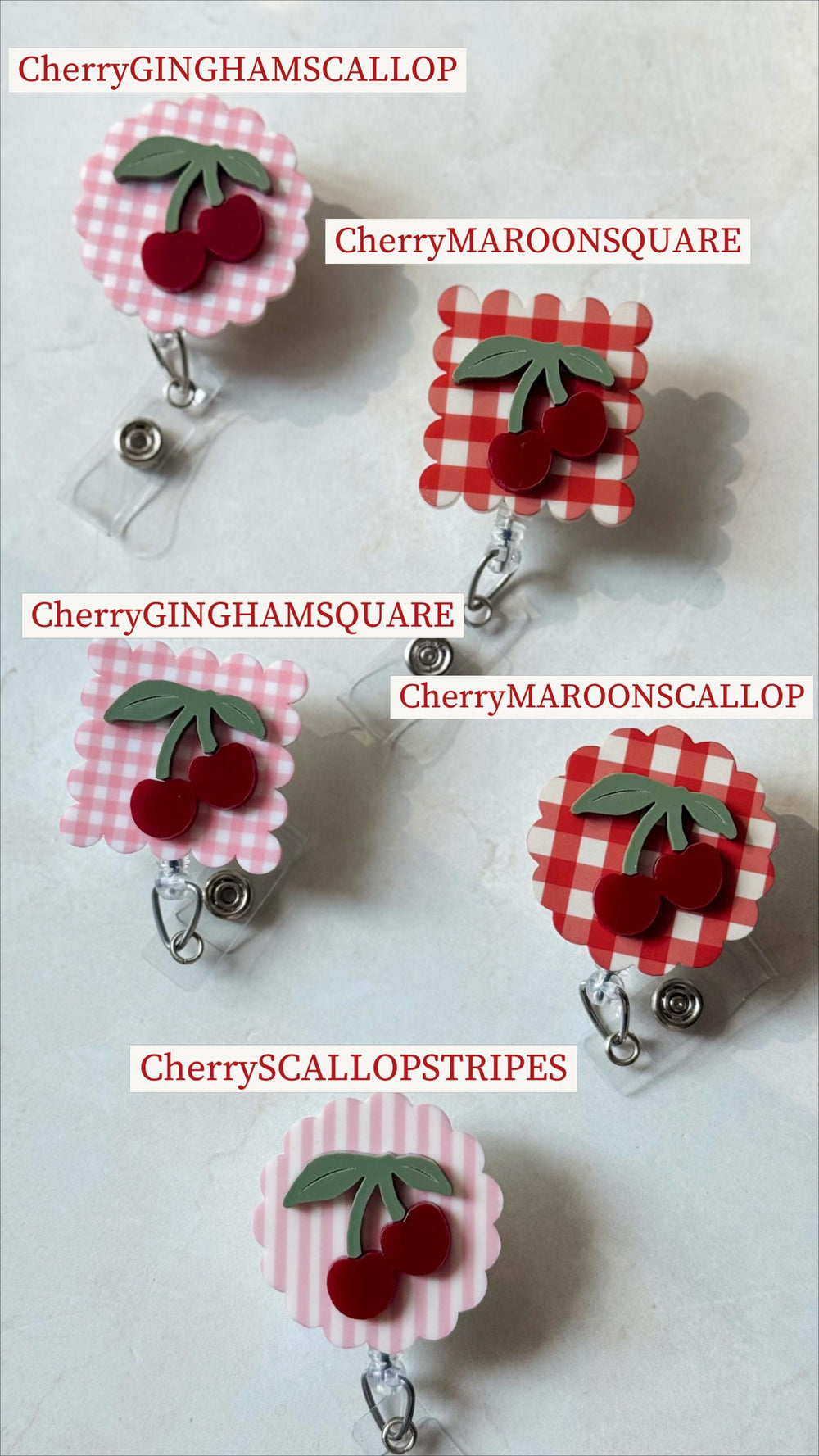 A collection of five badge reels with cherry designs. Each reel features a different gingham or striped pattern in pink or red, with a cherry and green leaf accent. The text on each reel reads "Cherry