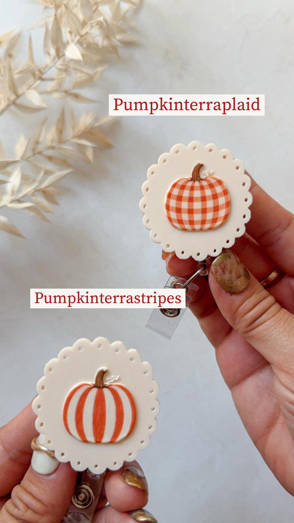 Two round badge reels with scalloped edges in off-white. One features an orange and white plaid pumpkin labeled Pumpkinterraplaid, and the other features an orange and white striped pumpkin labeled Pu