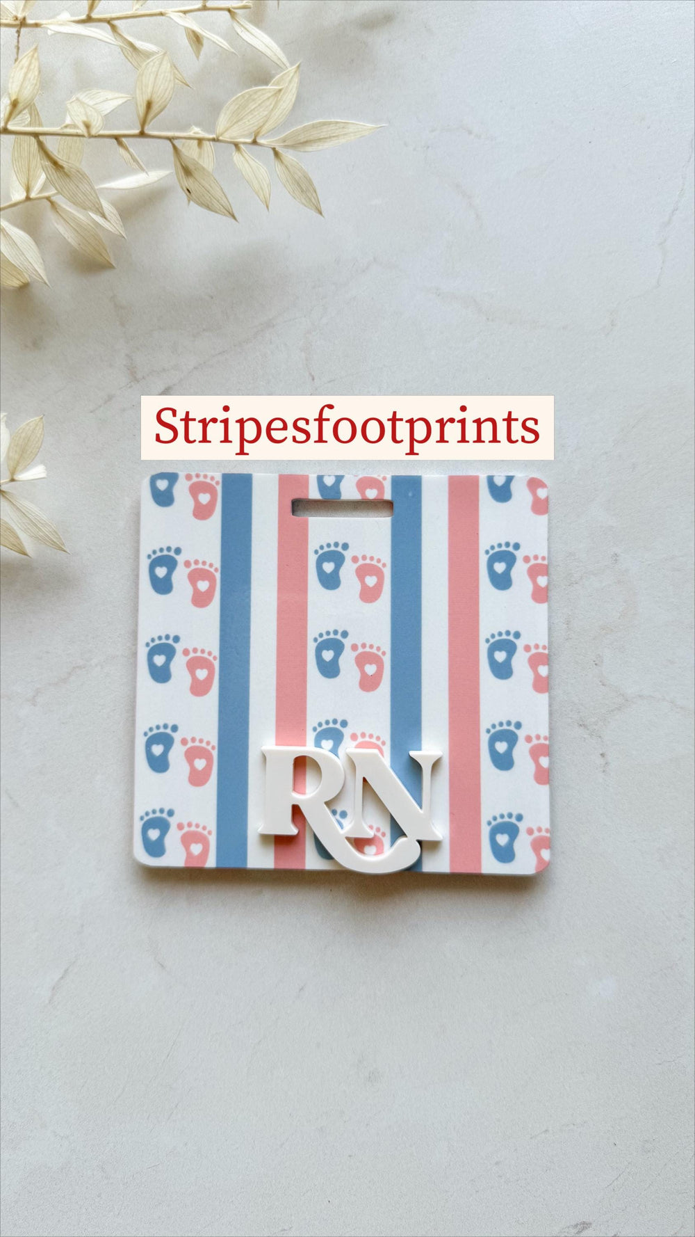 A white badge with a pattern of blue and pink baby footprints, alternating with blue and pink stripes. The badge has the letters "" in white and the text "Stripesfootprints".