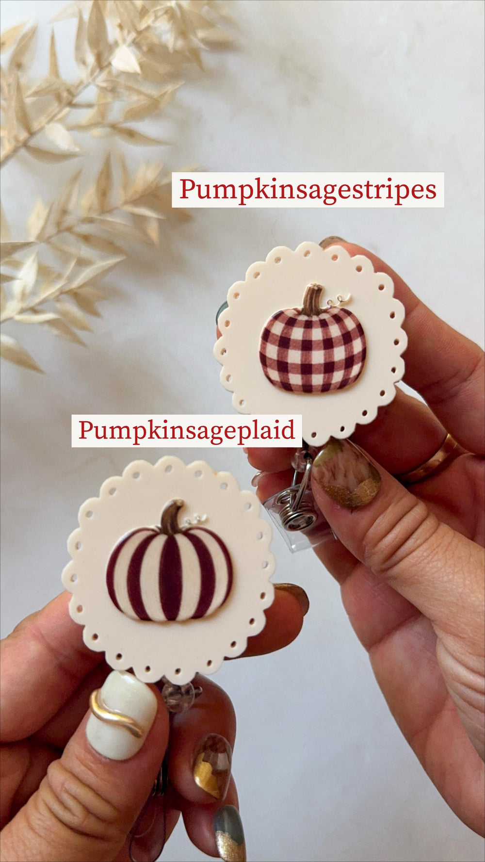Two circular badge reels with scalloped edges in off-white. One features a brown and white plaid pumpkin with the text Pumpkinsagestripes, and the other displays a dark red striped pumpkin with the te
