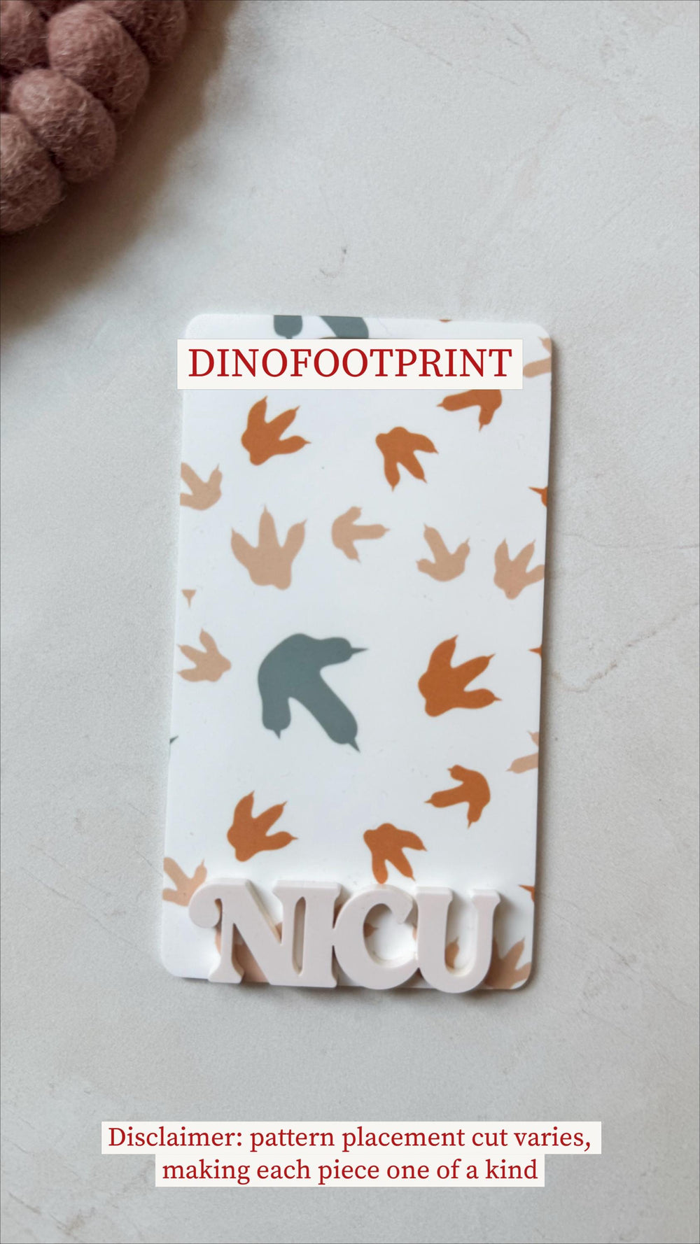 A rectangular white plaque with a pattern of orange and tan dinosaur footprints. The text "DINOFFOTPRINT" is at the top, and "" is at the bottom in a 3D font. The disclaimer text reads: "pattern place