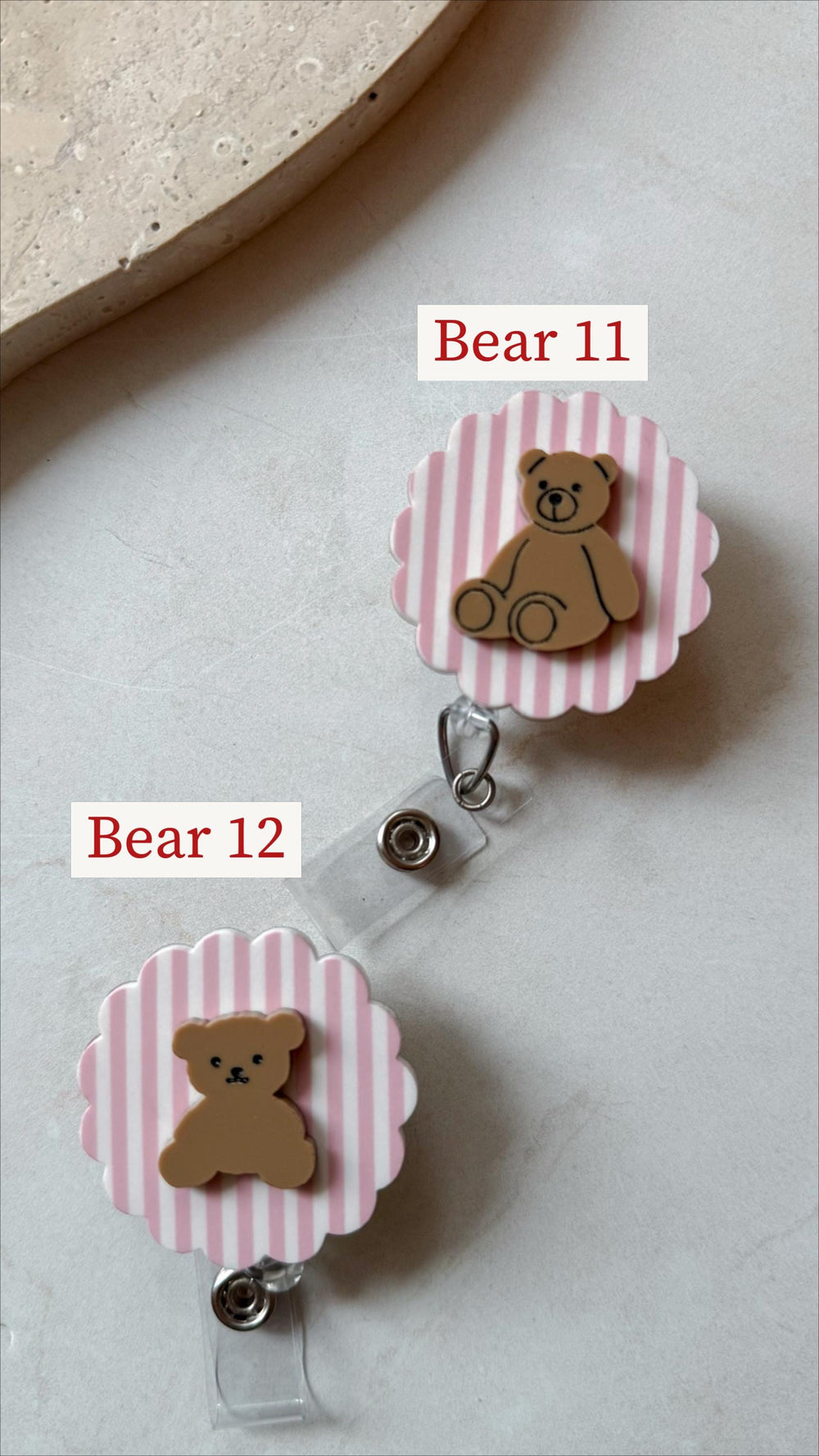 Two retractable badge holders with a pink and white striped background and a brown teddy bear design. The text "Bear 11" and "Bear 12" are printed on the image.