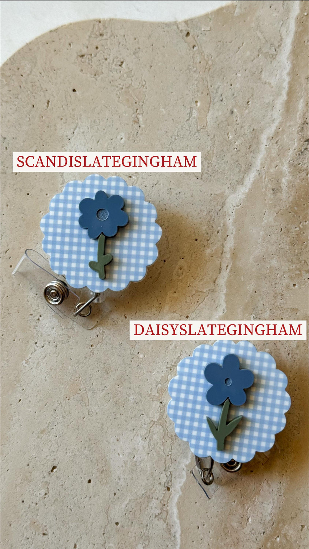 Two flower-shaped badge reels. Each reel features a blue gingham pattern with a blue flower and green stem. The text "SCANDISLATEGINGHAM" and "DAISYSLATEGINGHAM" are printed on the image.