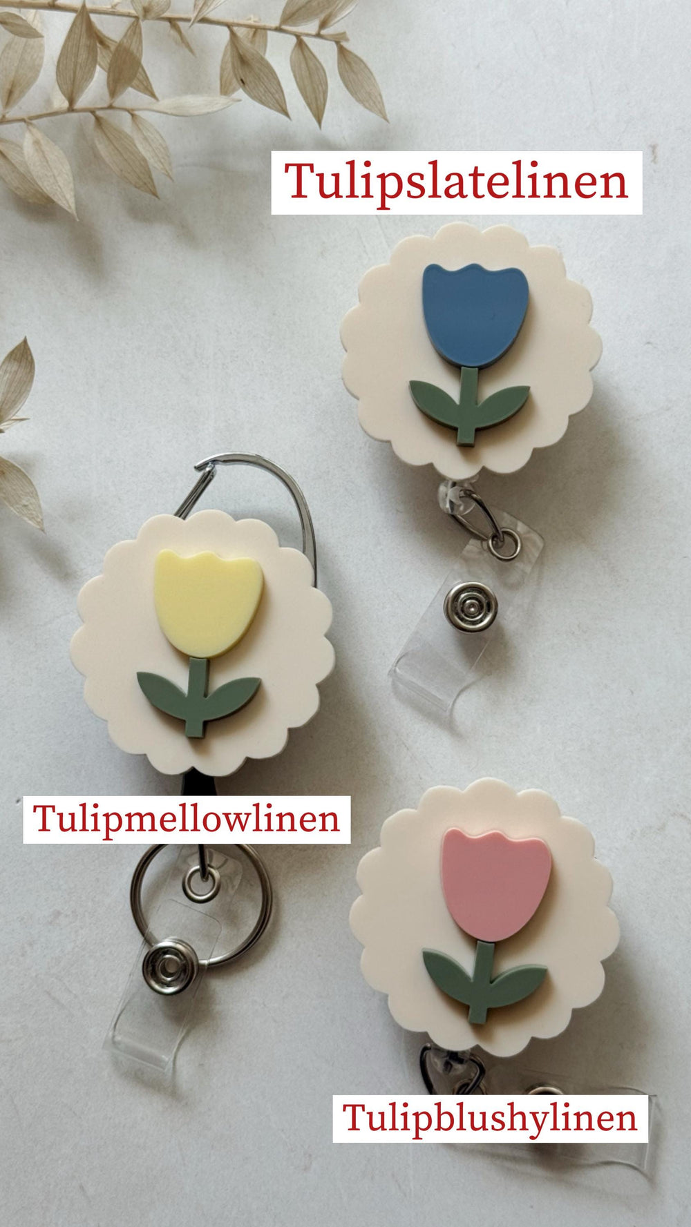 Three floral badge reels with different colored tulip designs. The tulips are blue, yellow, and pink, with green stems and leaves, set against a cream-colored background. The text "Tulipslatellinen", 